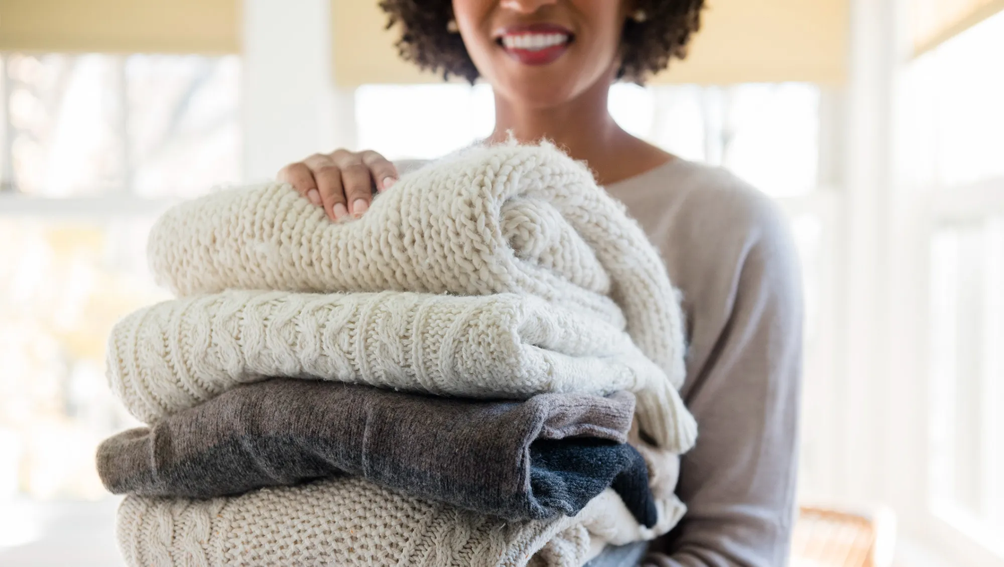woman with a stack of sweaters