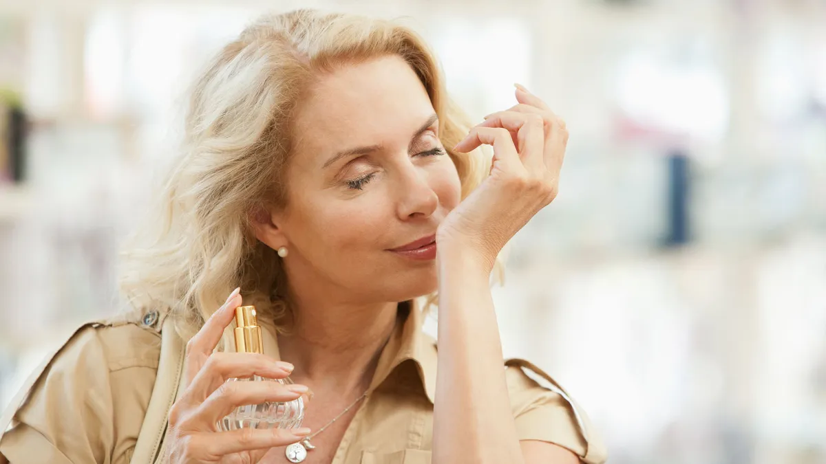 Smiling woman testing perfume in store