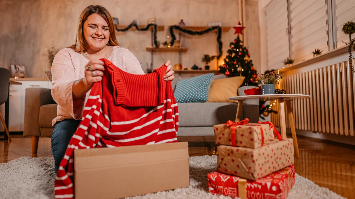 Young Plus Size Woman Unwrapping A New Sweater For Christmas