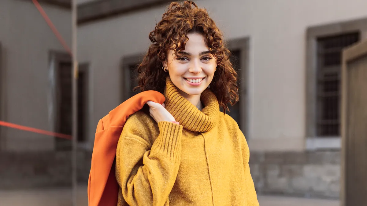 Smiling woman with shopping bags on footpath