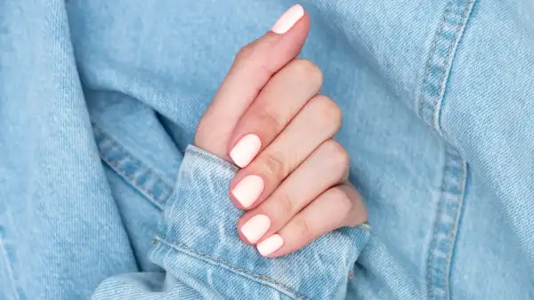 Bright neon red manicure on female hands on the background of jeans. Nail design. Beauty hands.