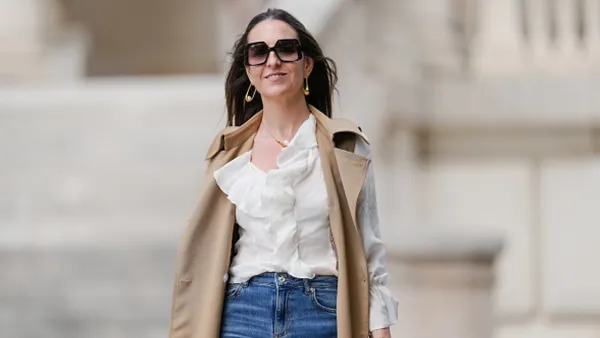 woman wearing white fall top, beige vest and blue jeans