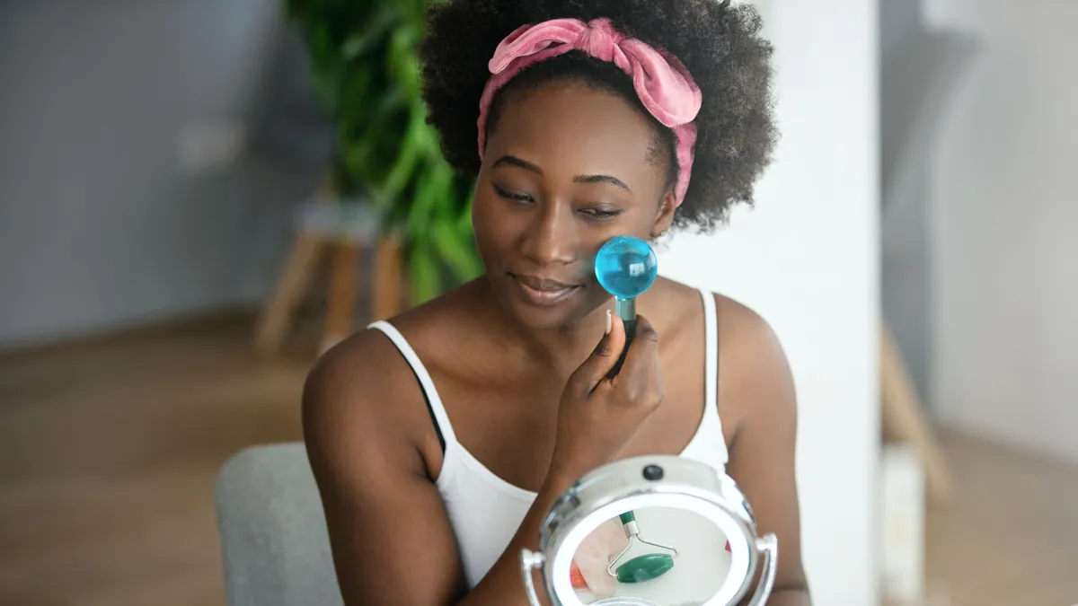 Young beautiful woman enjoying a facial massage with ice globes at home.
