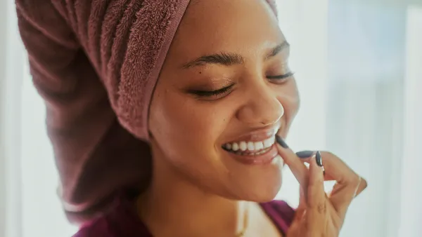 A close-up shot of a woman applying lip balm during her daily skin care routine. Stock photo with copy space