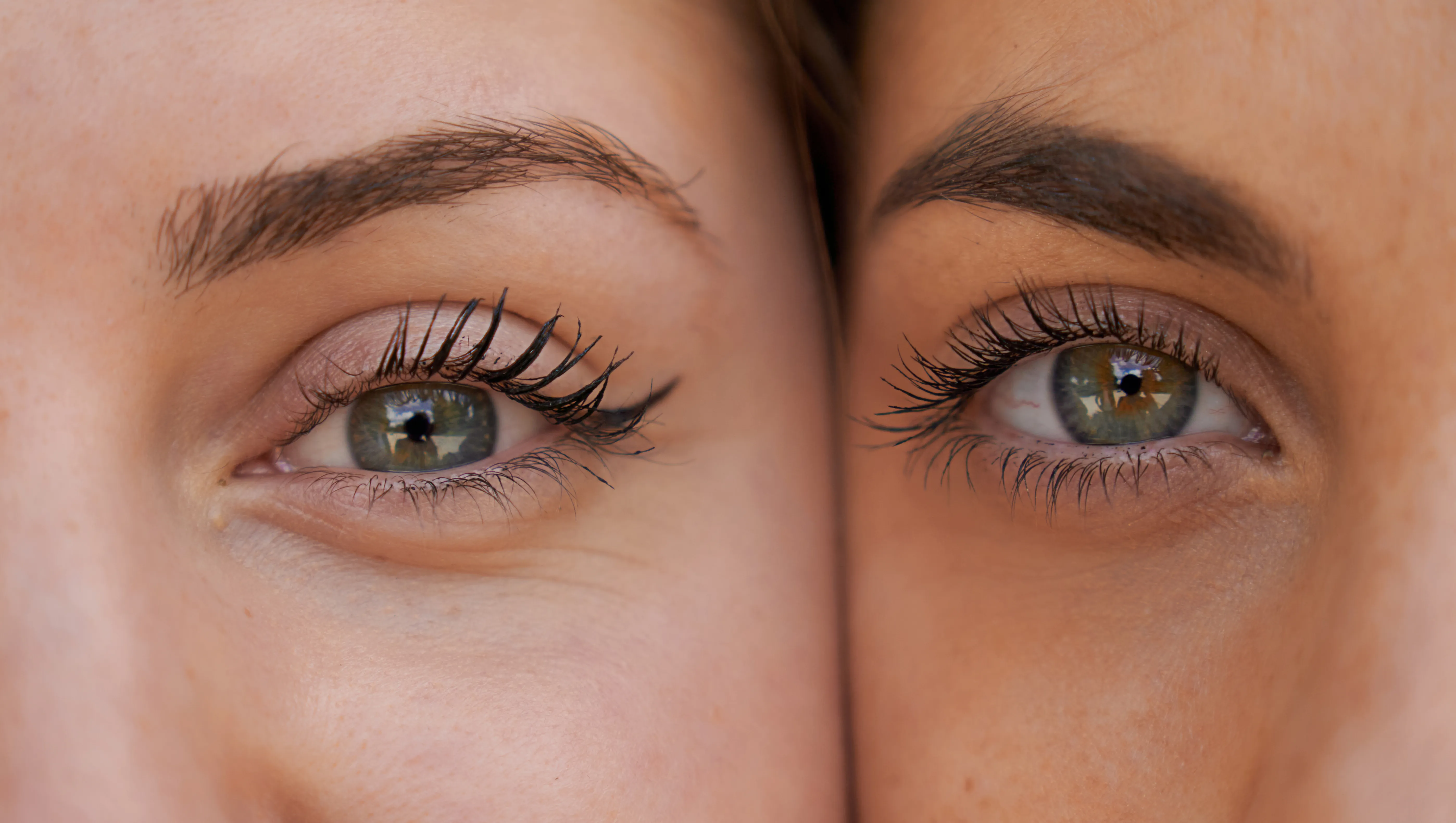 Close up view of two women with her faces next to each other while looking at the camera.