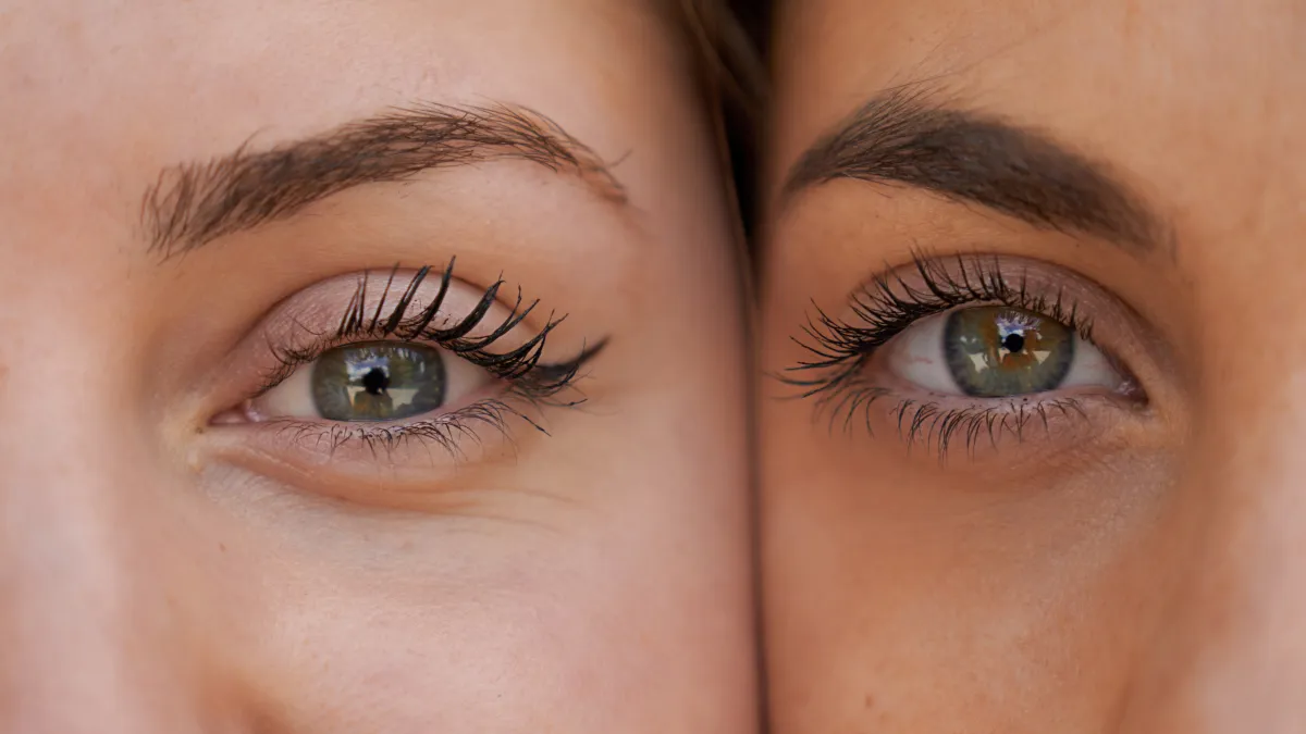 Close up view of two women with her faces next to each other while looking at the camera.