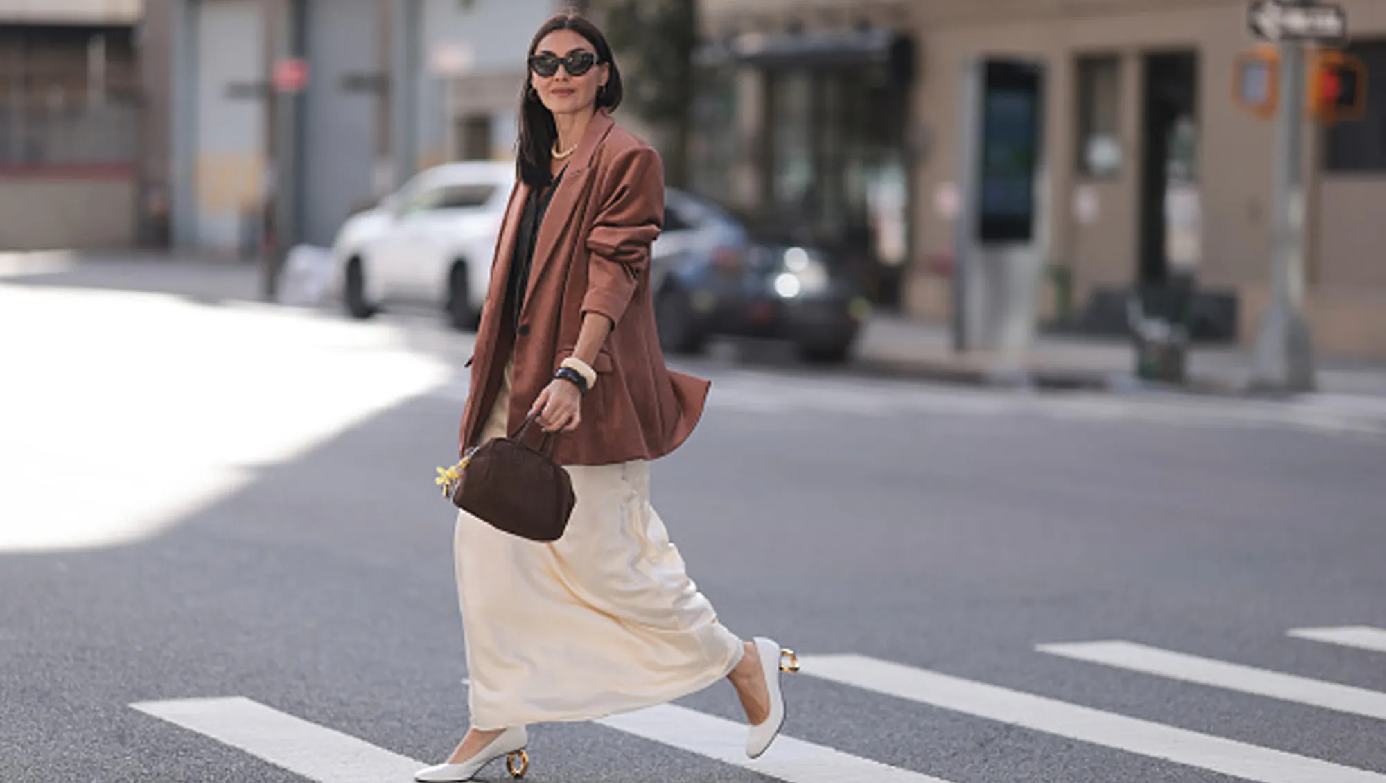 woman wearing brown blazer and cream skirt on street