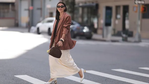 woman wearing brown blazer and cream skirt on street