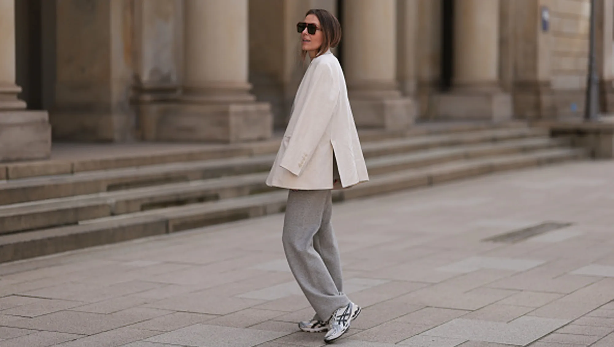 woman wearing sneakers, white blazer and gray pants