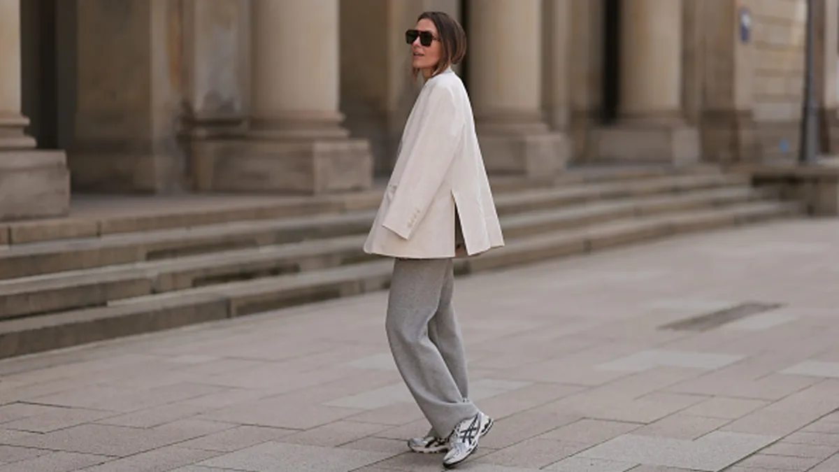 woman wearing sneakers, white blazer and gray pants