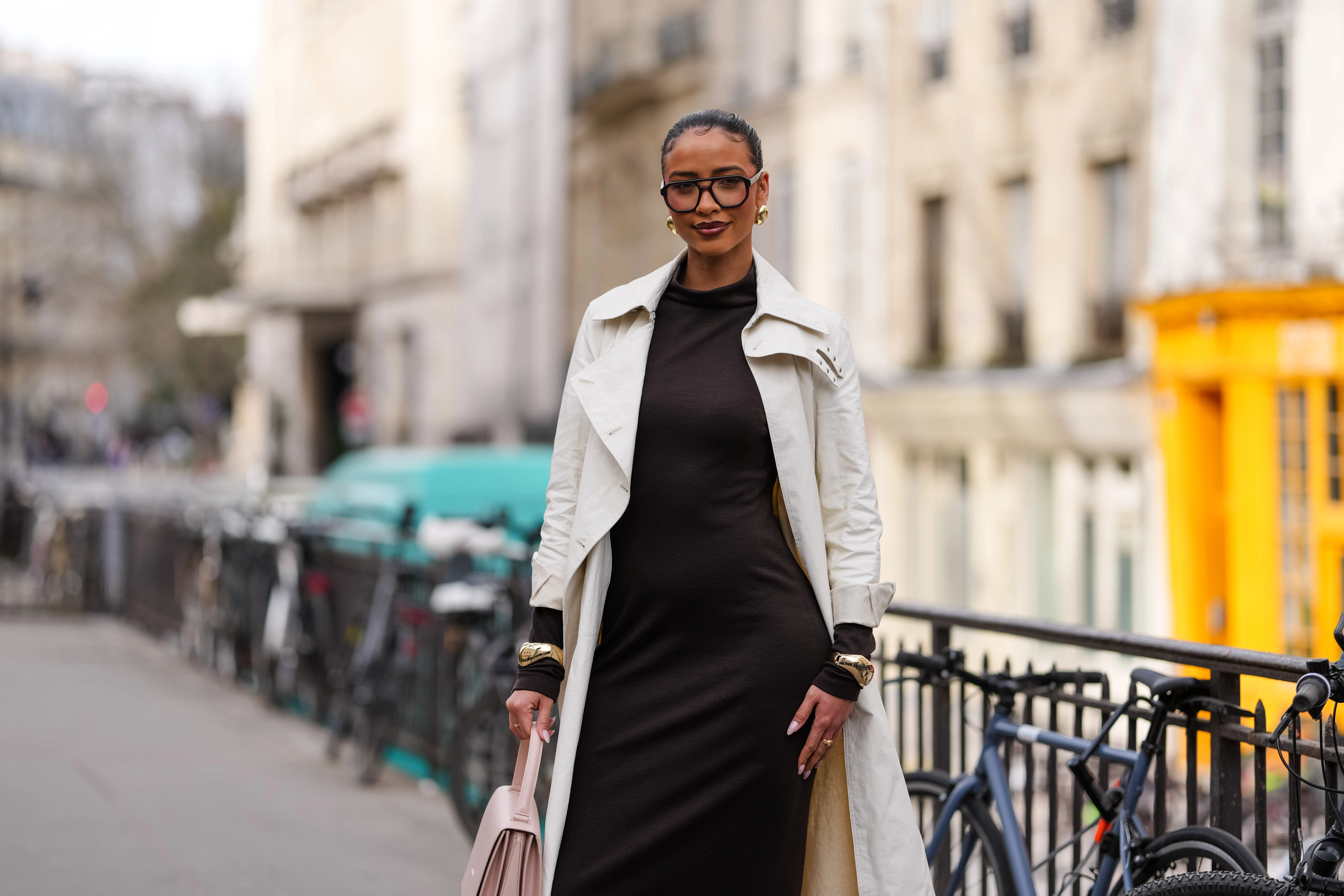 PARIS, FRANCE - MARCH 09: Flora Coquerel wears black sunglasses, gold earrings, dark brown high neck long sleeve midi dress, cream trench coat, gold bracelets, outside Akris, during the Paris Fashion week Women's Fall/Winter 2025-2026 on March 9, 2025 in Paris, France. (Photo by Edward Berthelot/Getty Images)