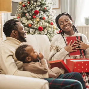 Young family unwrapping gifts on Christmas morning. Mother is getting cookbook.