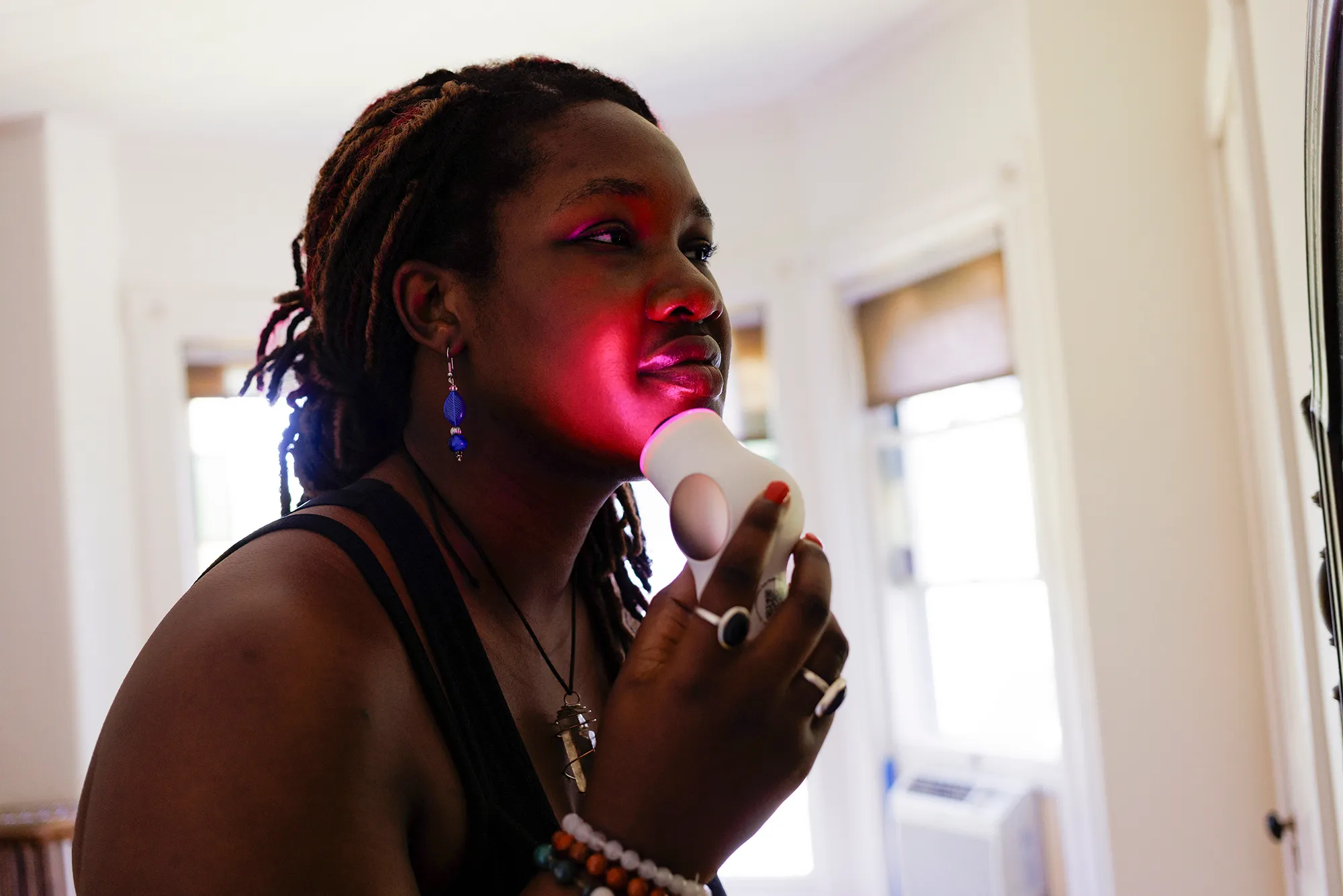 Young woman using red light therapy on face