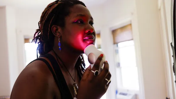Young woman using red light therapy on face