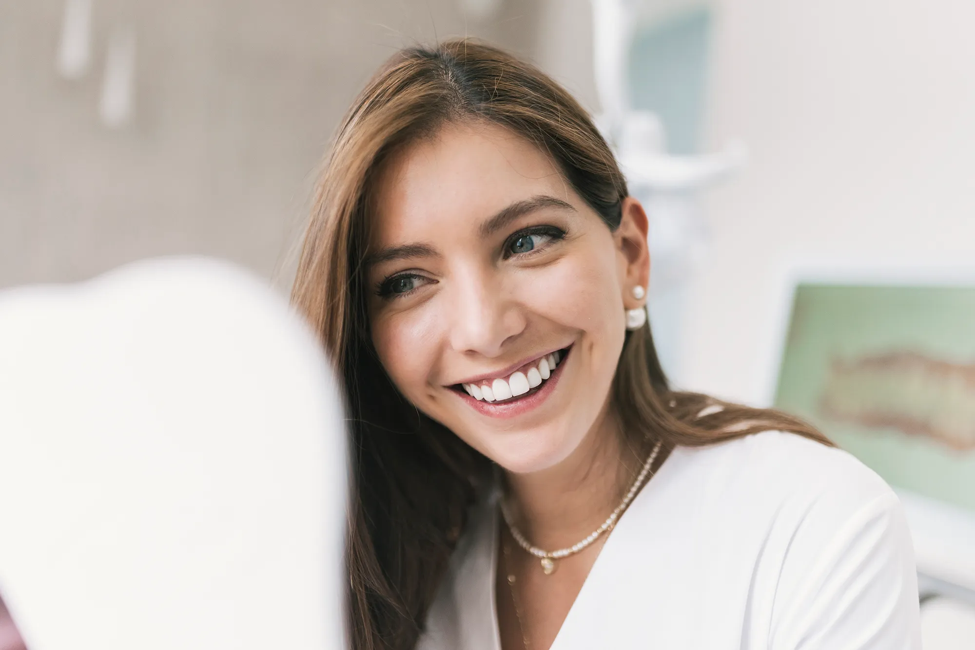 Happy woman looking at mirror at dentist's clinic