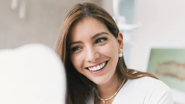 Happy woman looking at mirror at dentist's clinic