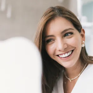 Happy woman looking at mirror at dentist's clinic