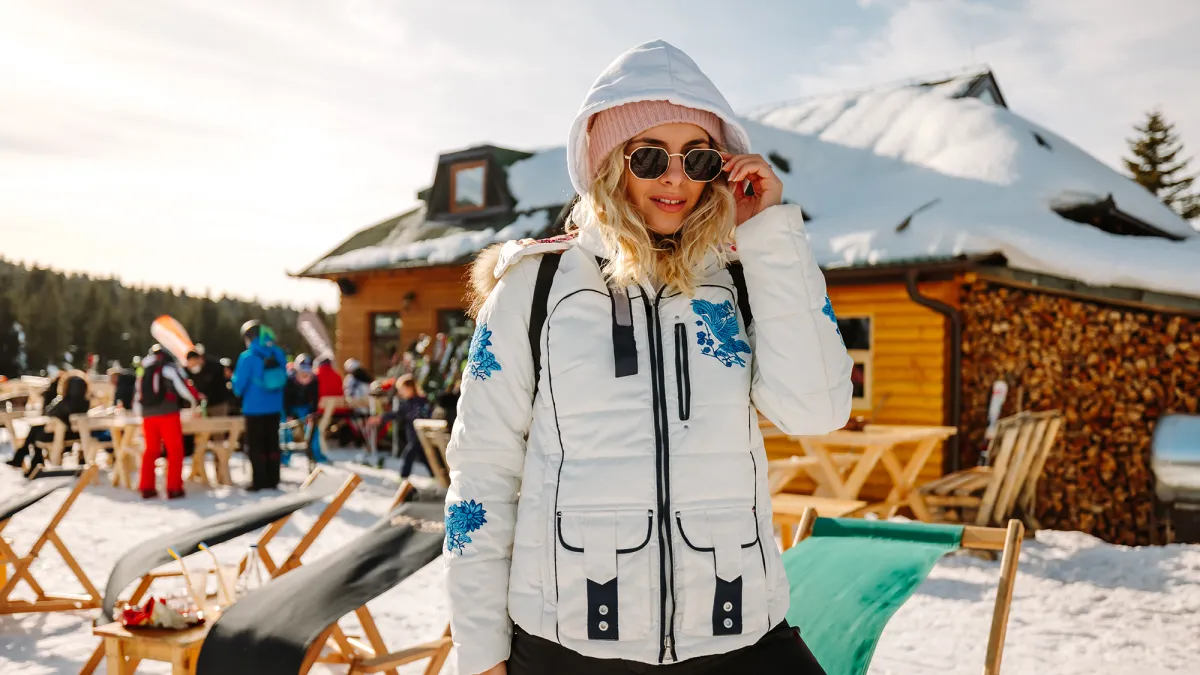 Beautiful young woman posing in ski resort on sunny winter day