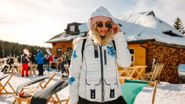 Beautiful young woman posing in ski resort on sunny winter day
