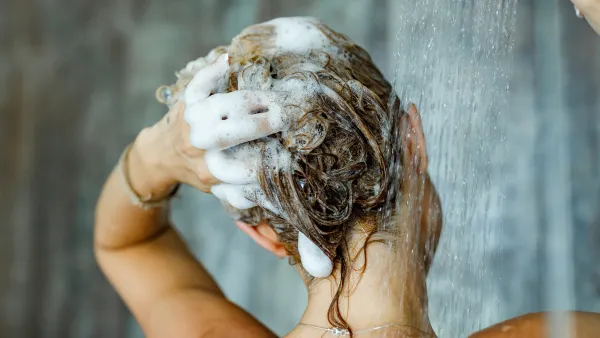 Back view of a woman washing her hair with a shampoo in bathroom. Copy space.