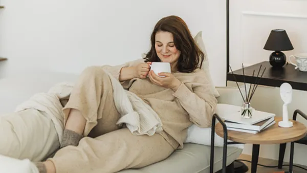 woman wearing beige loungewear set sipping a cup of tea