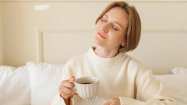 woman wearing loungewear in bed drinking coffee