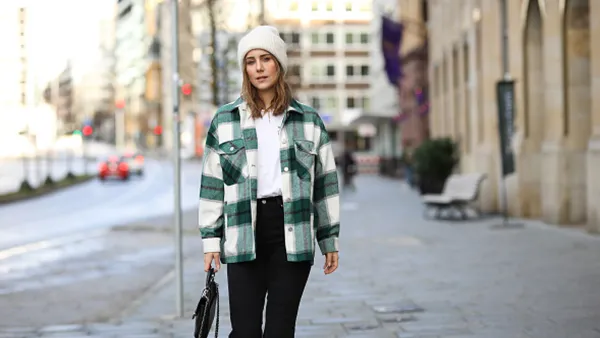 woman wearing green plaid shacket, black pants and white beanie