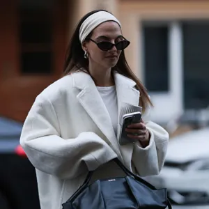 woman wearing white coat and head band and black sunglasses