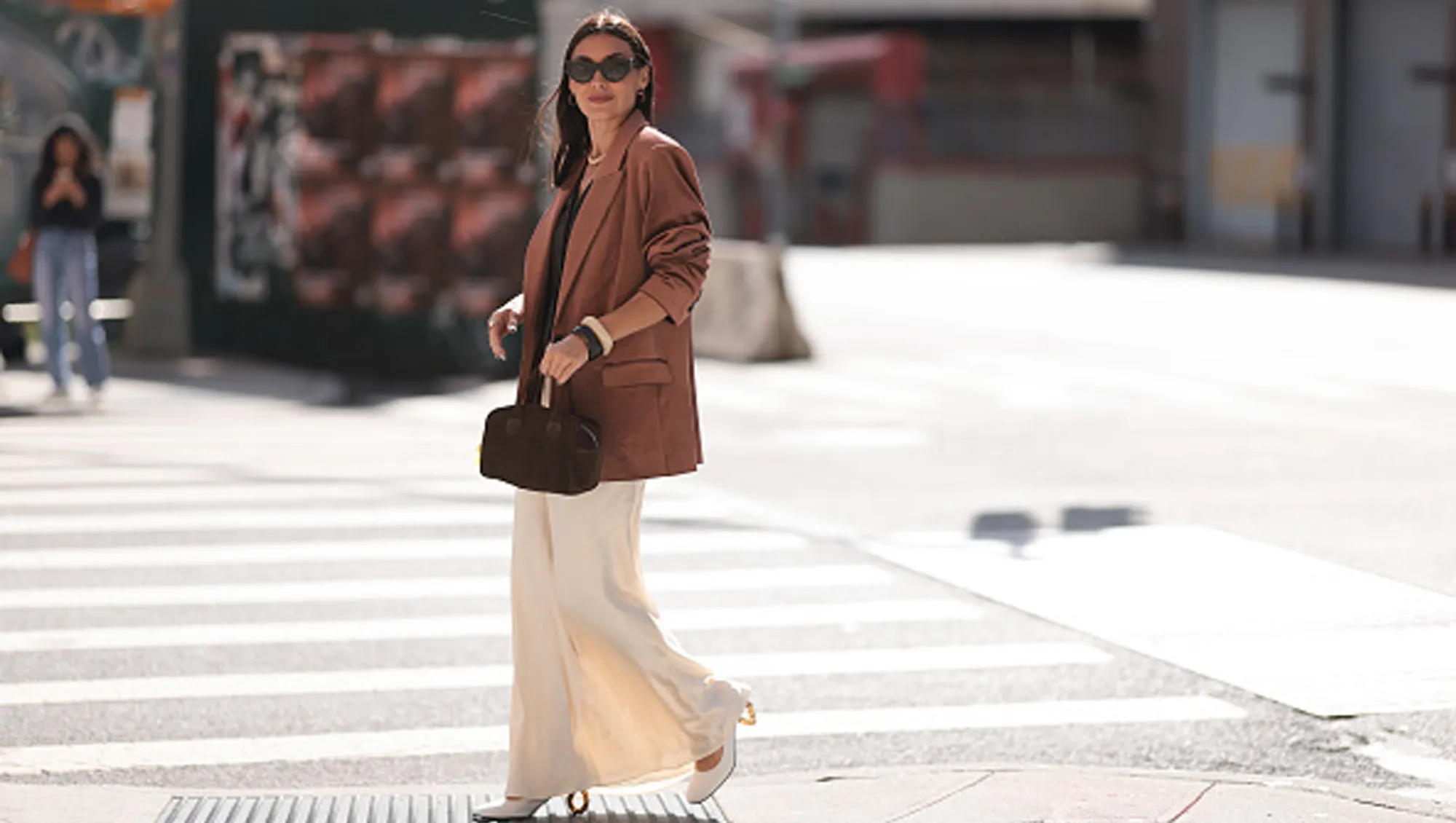 woman wearing brown blazer, white skirt and brown bag walking on street