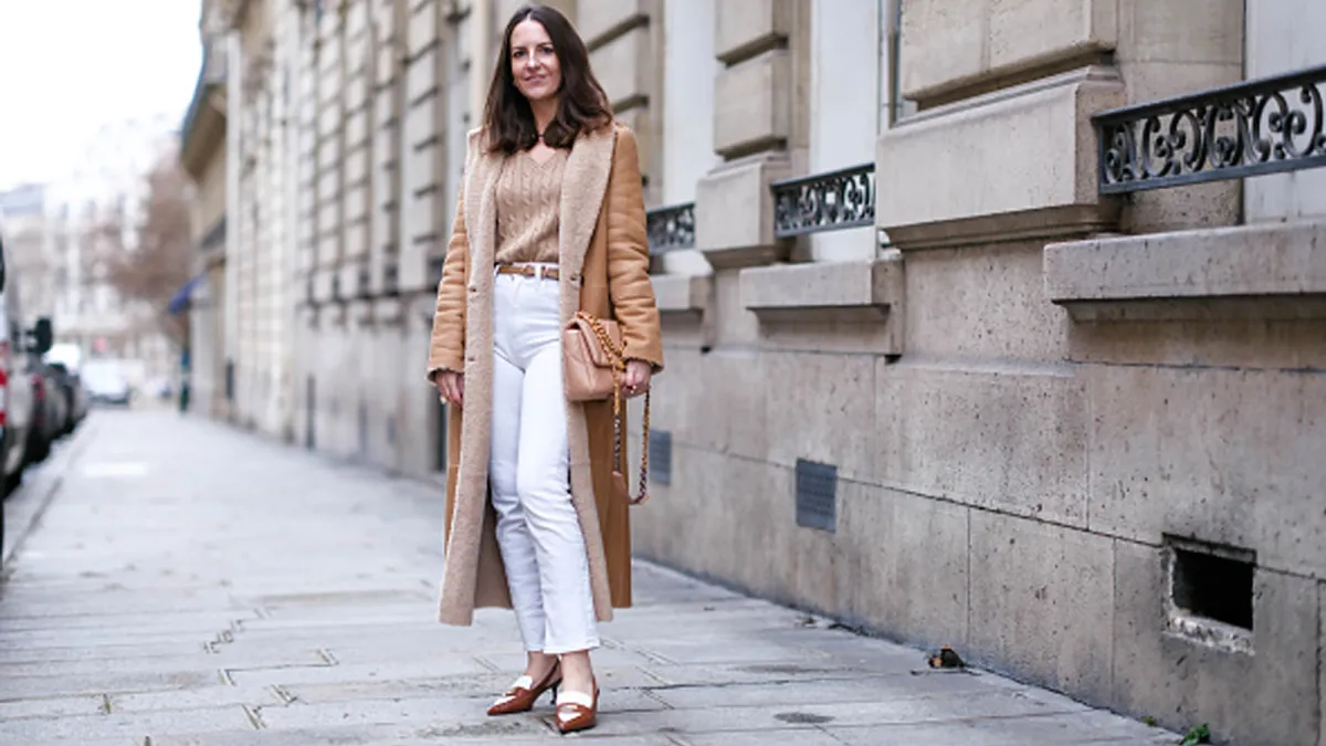 woman wearing beige sweater, white pants and tan jacket