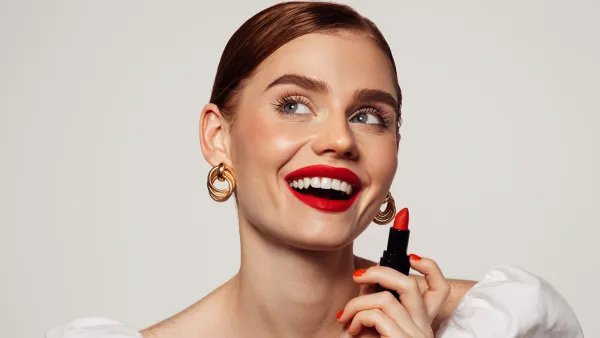 Beautiful emotional woman with bright make-up applying red lipstick