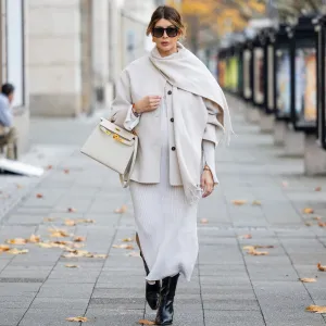Victoria Scheu wears knitted white dress H&M, scarf jacket with fringes Cos, sunglasses Givenchy, Kelly Bag Craie Hermes, black ankle boots on November 27, 2024 in Berlin, Germany.