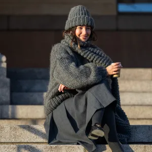 COPENHAGEN, DENMARK - FEBRUARY 01: Benthe Liem sitting drinking coffee wears grey beanie, knit, scarf, skirt, black Prada bag outside Marimekko during the Copenhagen Fashion Week AW24 on February 01, 2024 in Copenhagen, Denmark. (Photo by Christian Vierig/Getty Images)