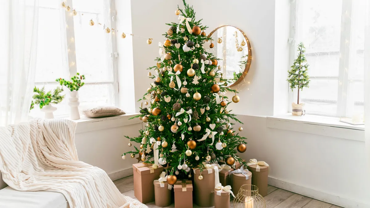 White and spacious domestic living room decorated with Christmas fir tree and pastel holiday decor. Festive craft gift boxes and wrapped presents for family and friends. Cozy celebrations at home