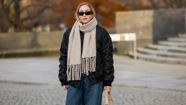 BERLIN, GERMANY - NOVEMBER 26: Sonia Lyson wears jeans and jacket Closed, FTC scarf, bag Nanushka, sunglasses Prada on November 26, 2024 in Berlin, Germany. (Photo by Christian Vierig/Getty Images)