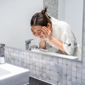 Woman washing her face with facial foam and water