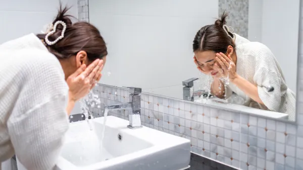 Woman washing her face with facial foam and water