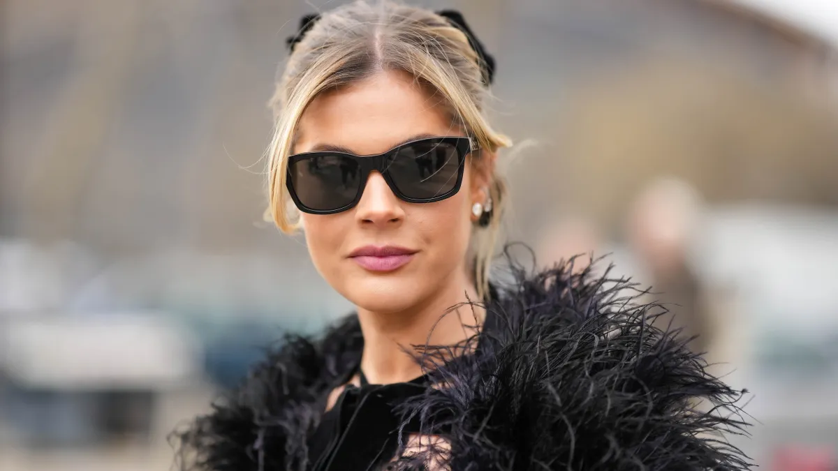 PARIS, FRANCE - MARCH 07: Lala Rudge wears black sunglasses, diamonds earrings, a black velvet with lace print pattern halter-neck long dress, a black feathers cloak, outside Chanel, during Paris Fashion Week - Womenswear Fall Winter 2023 2024, on March 07, 2023 in Paris, France. (Photo by Edward Berthelot/Getty Images)