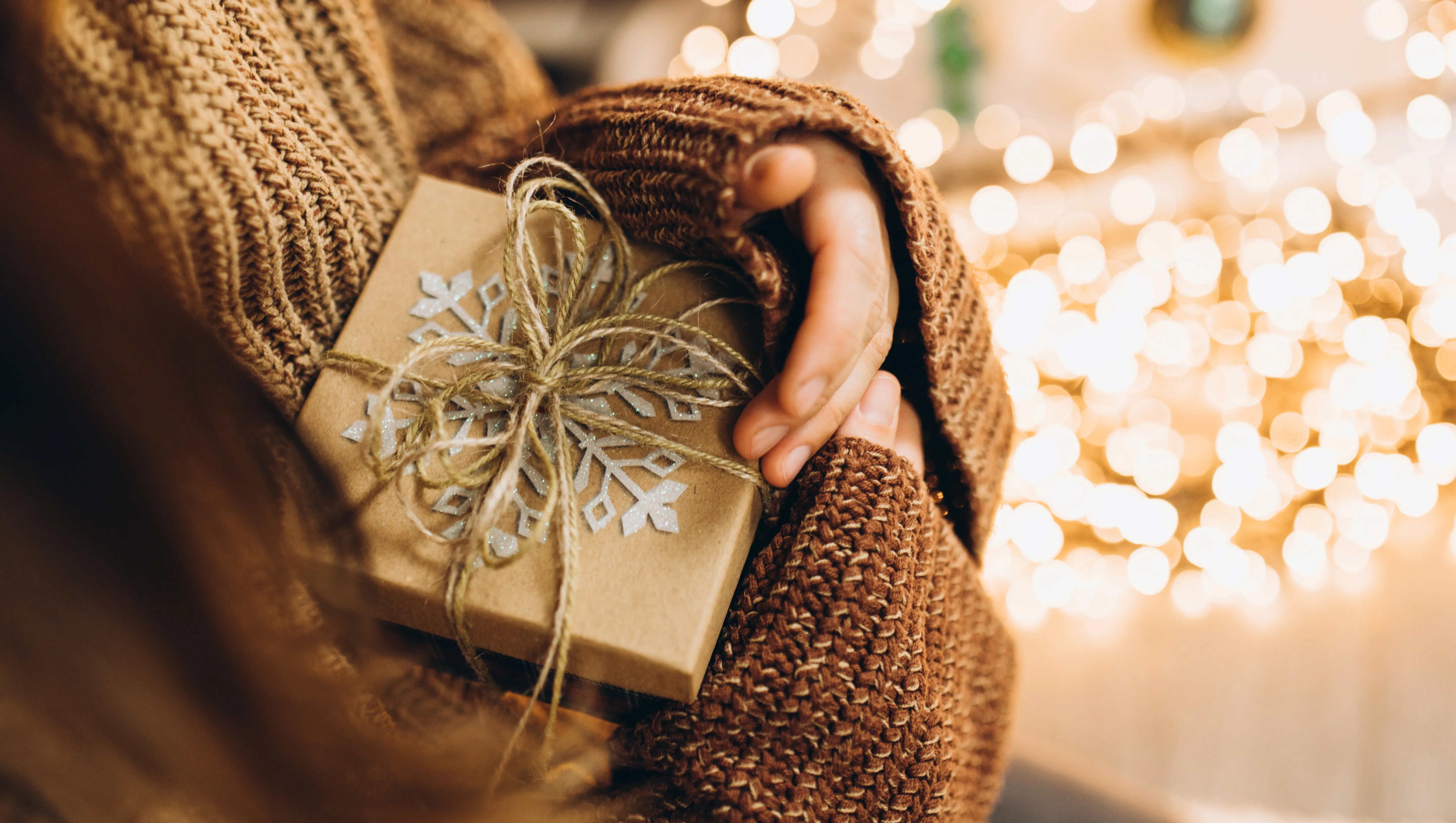 Christmas present in female hands against the background of Christmas lights.