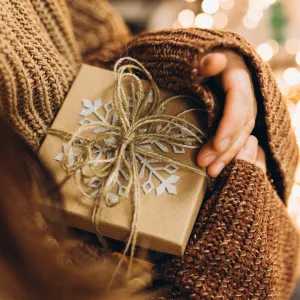 Christmas present in female hands against the background of Christmas lights.