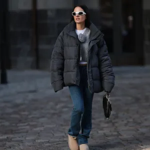 BERLIN, GERMANY - NOVEMBER 30: Anna Winter seen wearing Bottega Veneta white sunglasses, white cotton top, Balenciaga black puffer winter jacket, Rotate grey wool knit v-neck sweater / pullover with a flower detail, blue denim long jeans / pants, Dior black leather Saddle bag and UGG beige platform suede leather winter boots, on November 30, 2023 in Berlin, Germany. (Photo by Jeremy Moeller/Getty Images)
