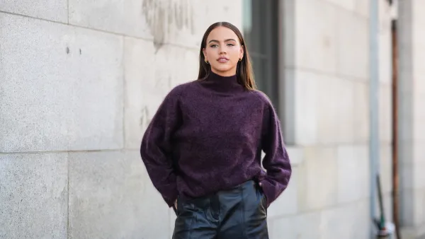 A guest wears dark purple oversized turtleneck sweater, shiny black leather shorts, outside Cos, during the New York Fashion week Spring/Summer 2025 on September 10, 2024 in New York, New York.