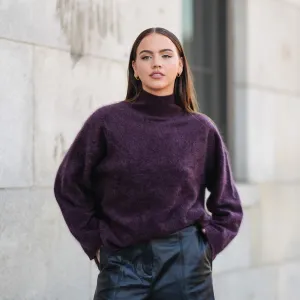 A guest wears dark purple oversized turtleneck sweater, shiny black leather shorts, outside Cos, during the New York Fashion week Spring/Summer 2025 on September 10, 2024 in New York, New York.
