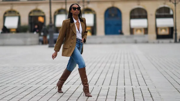 woman wearing blue jeans, brown jacket and boots