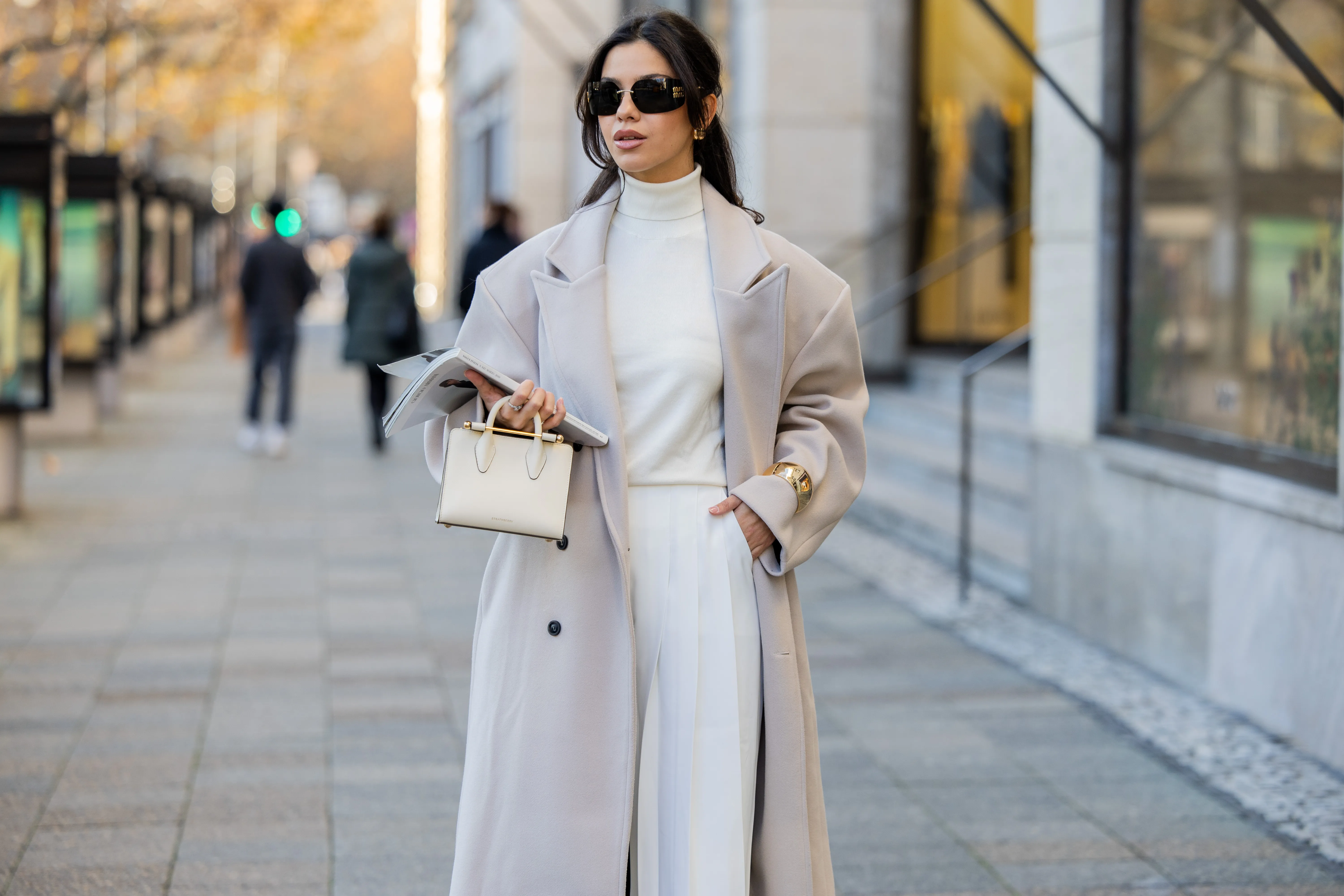 Bella Emar wears oversized grey double breasted sourceunknown coat, creme white turtleneck top Zara, white wide leg pants Frankie Shop, strathberry bag on November 30, 2024 in Berlin, Germany.