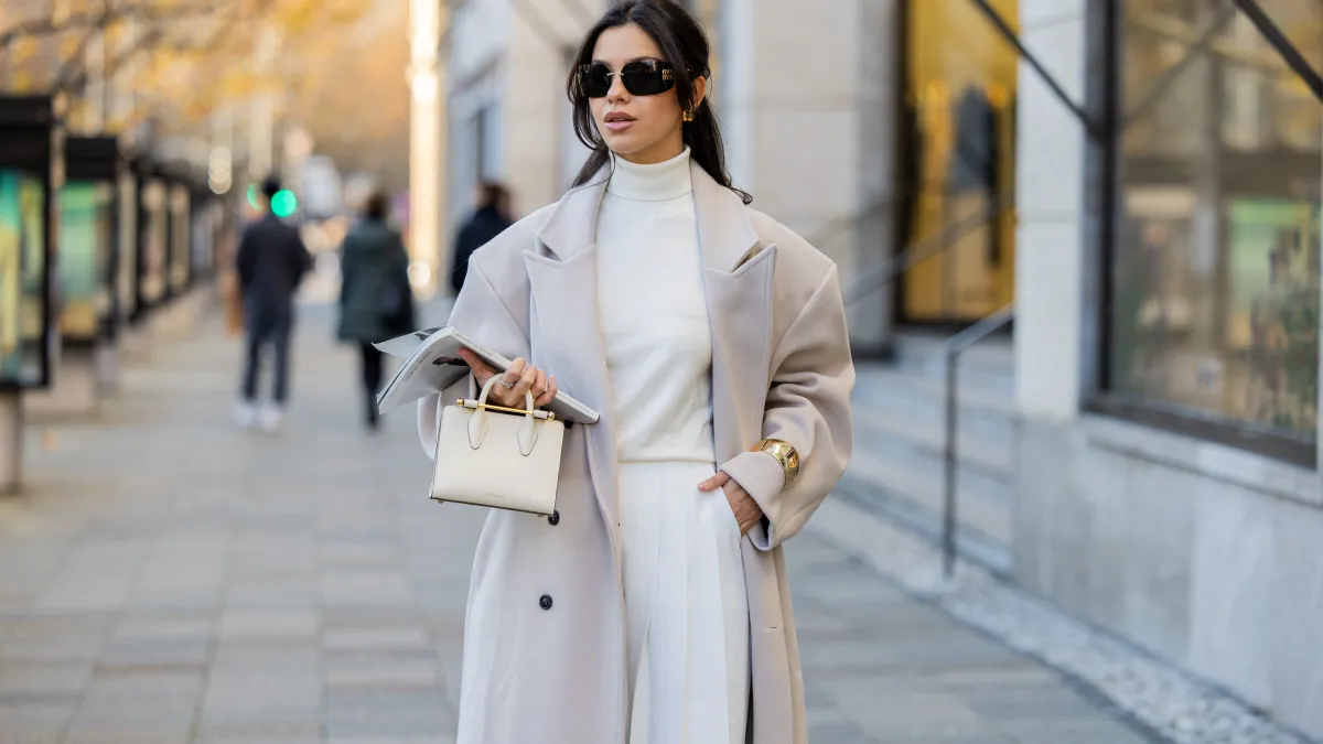 Bella Emar wears oversized grey double breasted sourceunknown coat, creme white turtleneck top Zara, white wide leg pants Frankie Shop, strathberry bag on November 30, 2024 in Berlin, Germany.