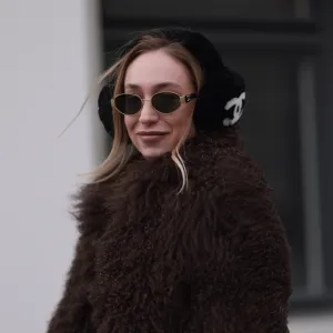 BERLIN, GERMANY - JANUARY 15: Sonia Lyson seen wearing Celine gold Triomphe metal sunglasses, Chanel black with white logo pattern fake fur ear muffs, Ducie London brown fake fur jacket / coat, on January 15, 2024 in Berlin, Germany. (Photo by Jeremy Moeller/Getty Images)