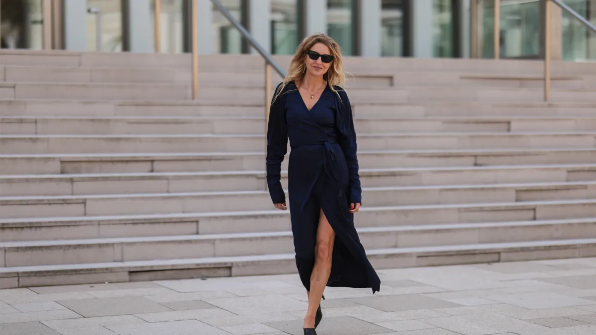 Sue Giers seen wearing a black Celine sunglasses, a dark blue silk midi dress from SoSue and black leather Bottega Veneta heels on June 09, 2022 in Hamburg, Germany.