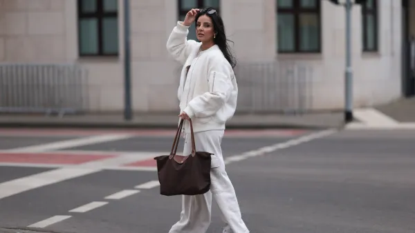 COLOGNE, GERMANY - FEBRUARY 14: Tara Tut seen wearing Gucci brown sunglasses, gold earrings, gold necklace, Zara creamy white cotton oversized sweater, matching Zara creamy white jogger pants / sweatpants, H&M white boucle bomber jacket, Longchamp brown nylon shopper bag and New Balance light pink leather sneakers, on February 14, 2024 in Cologne, Germany. (Photo by Jeremy Moeller/Getty Images)
