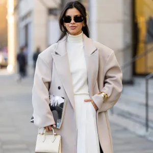 Bella Emar wears oversized grey double breasted sourceunknown coat, creme white turtleneck top Zara, white wide leg pants Frankie Shop, strathberry bag on November 30, 2024 in Berlin, Germany.